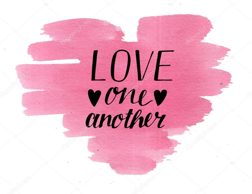 Hand lettering Love one another on watercolor heart.