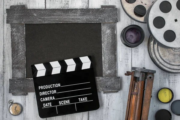 Clapperboard, reels of film and a tripod — Stock Photo, Image