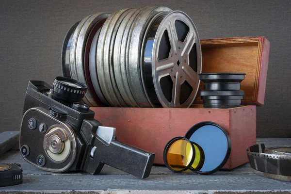 Bobine con film in una scatola di legno, lente e una vecchia macchina fotografica — Foto Stock