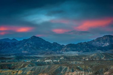Dağların üzerinde pembe bulutlarla sakin bir yaz akşamı.