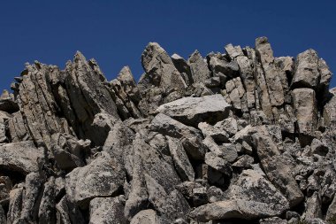 Kaliforniya 'nın batı kıyısındaki keskin kayalar güneşli bir yaz gününde mavi gökyüzüne karşı alınır.