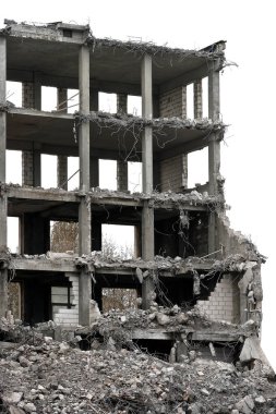 Yıkılmış taş yığını ve çıkıntılı metal destek çubukları olan bir bina.