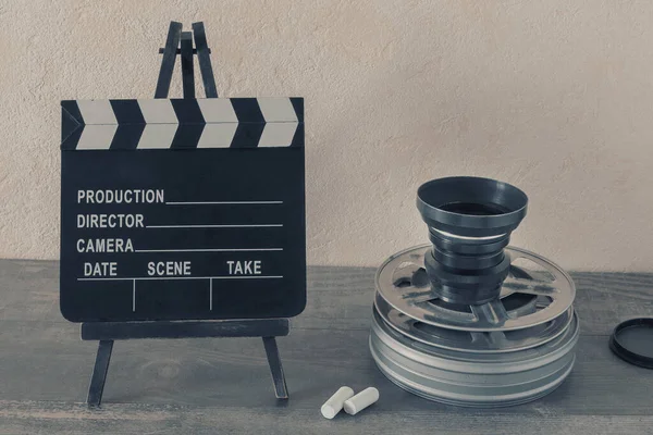 映画のある金属製の箱 映画カメラ用のレンズ チョークの破片が入ったクラッパーボードがスタジオにあります ストックフォト