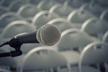 Boş bir konser salonundaki metal bir standın üzerinde sandalyeli gümüş bir mikrofon duruyor.
