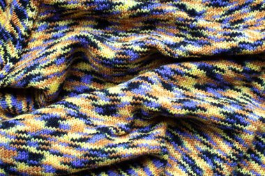 Kumaşta pliseler, sarı mavi kahverengi kahverengi renkli örgü kumaşlar, kıvrımlar.