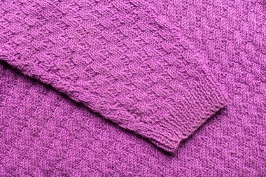 Beyaz arka planda örülmüş bir süvetere örülmüş bir kol, mavi sarı siyah kahverengi renk.