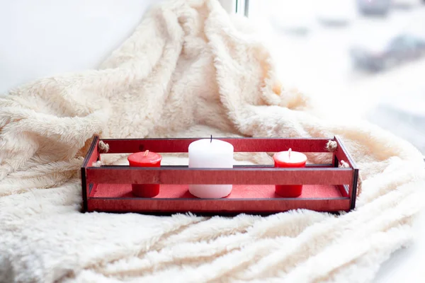 white, red candles, a red wooden box on a beige blanket