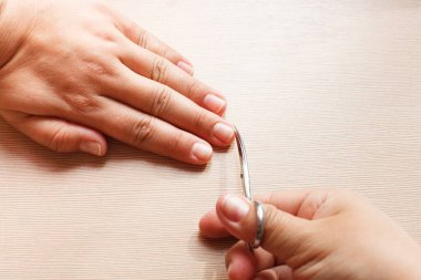 Eller yakın çekim, bir kız kendine manikür yapıyor, tırnak makası.