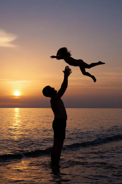 Sylwetki Mężczyzny Dziewczyny Plaży Zachodzie Słońca Ojciec Wyrzuca Córkę Powietrze — Zdjęcie stockowe