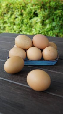 Tabakta bir yığın yumurta ve masada yeşil arka planı olan iki yumurta.