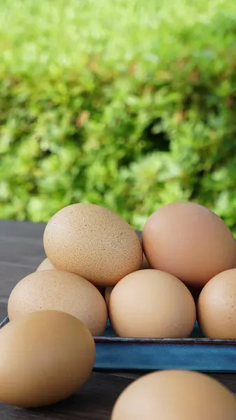 Tabakta bir yığın yumurta ve masada yeşil arka planı olan iki yumurta.