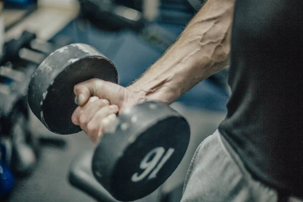 In this photo we see a dumbbell in the hand which clearly shows the veins and a dumbbell of 16 kilograms. From this we can assume that this is happening in the gym.