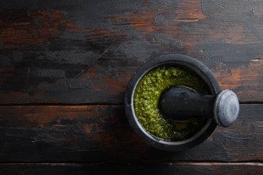 Eski ahşap masa fotokopi alanı üzerinde siyah harçla taze fesleğen pesto hazırlığı.