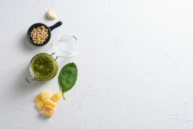 Cam kavanozda yeşil pesto fesleğen sosu. Beyaz arkaplan görünümlü parmesan fesleğen çam fıstığı içerikli metin için düz alan yatıyordu.
