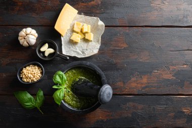 Siyah harçla taze fesleğen pesto hazırlama. Üzerinde İtalyan tarifi malzemeleri var. Eski ahşap masa fotokopi alanının üstünde.
