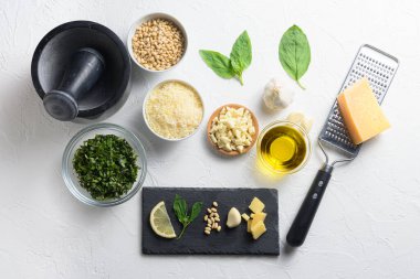 İtalyan pesto için farklı malzemeler. Izgara parmesan peyniri, fesleğen yaprağı, çam fıstığı, zeytin yağı, sarımsak beyaz taş kenarlı üst görünümde.
