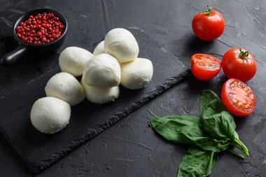 Mozzarella peyniri, fesleğen domates vişneli siyah arka plan siyah taş levha .