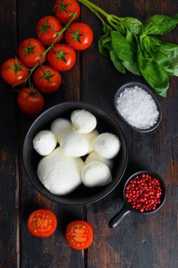 Mozzarella peynirli toplar, kiraz domatesleri ve ahşap masada taze taze organik fesleğen biberleri..