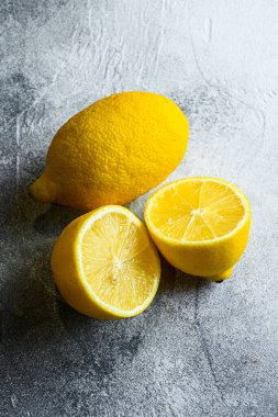 Lezzetli dilimlenmiş turunçgil meyvesi. Sarı limon ve limon. Yarısı kesilmiş. Taze narenciye meyveleri, gri arka planda C vitamini kaynağı