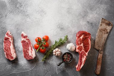 Çiğ sığır eti, siyah angus, kovboy bifteği ya da Chuck rolle kesilmiş İskoç filetosu. Gri taş masa üzerinde Amerikan bıçak ile kesilmiş. Üst çerçeve, baharatlar, domatesler, sarımsak, biberiye ile uyumlu. Metin için boşluk