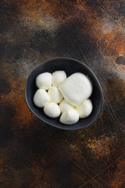Siyah kasede Mozzarella peynir topları farklı boyutlarda metin için kırsal yüzey üzerinde koyu metal tarzı üst görünüm.