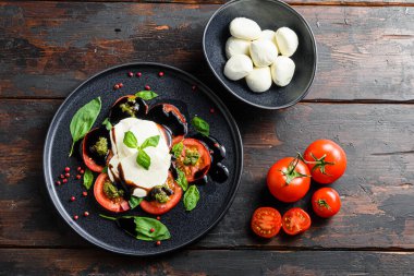 Caprese salatası kiraz domatesleri, mozzarella peyniri, fesleğen, pesto sosu. Üst manzara, eski ahşap arkaplan.