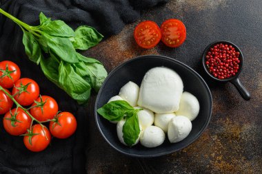Mozzarella peyniri, kiraz domatesleri ve fesleğen yaprakları koyu bir rustik metal zemin üzerinde gül biberi, Caprese salatası üst görünümü için İtalyan mutfak malzemeleri