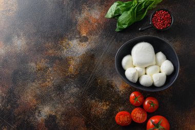 Taze kiraz domatesleri, fesleğen yaprakları, mozzarella peyniri ve eski kırsal metal arka planda zeytinyağı. Caprese salata malzemeleri. Seçici odaklanma. Metin için üst görünüm alanı.
