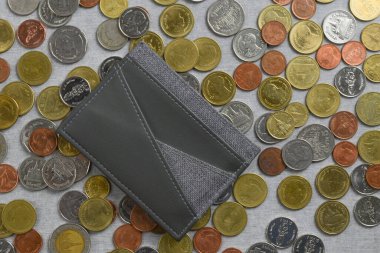 Gri çimento desenli arka planda bir yığın Tayland Baht madeni parasının üzerinde cep / kart tutucu yeri. Mali ve masraf kavramı.