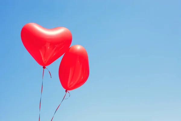 Two red heart shaped balloons
