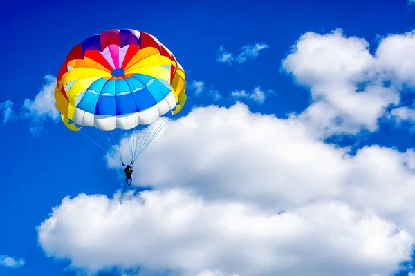 Paragliding parachuting sport in the blue cloudy sky.