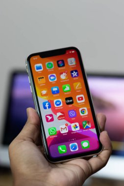 iPhone 11 'in arkası. Elinde beyaz varyant.