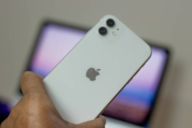 iPhone 11 'in arkası. Elinde beyaz varyant.