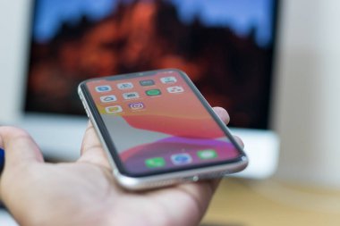 iPhone 11 'in arkası. Elinde beyaz varyant.