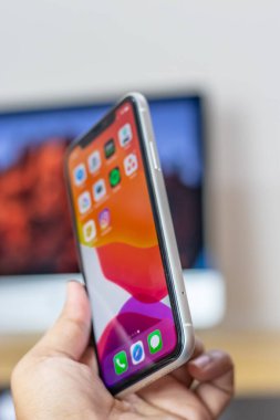 iPhone 11 'in arkası. Elinde beyaz varyant.