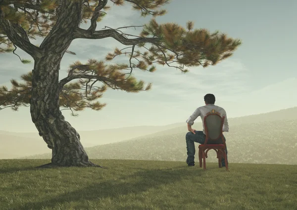 Jeune homme assis sous un arbre — Photo