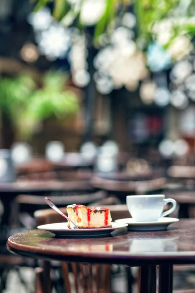 Slice of cheesecake with cherry and cup tea