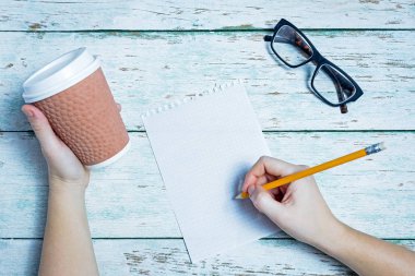 Eller bir cam, kağıt, kalem ahşap arka plan üzerinde