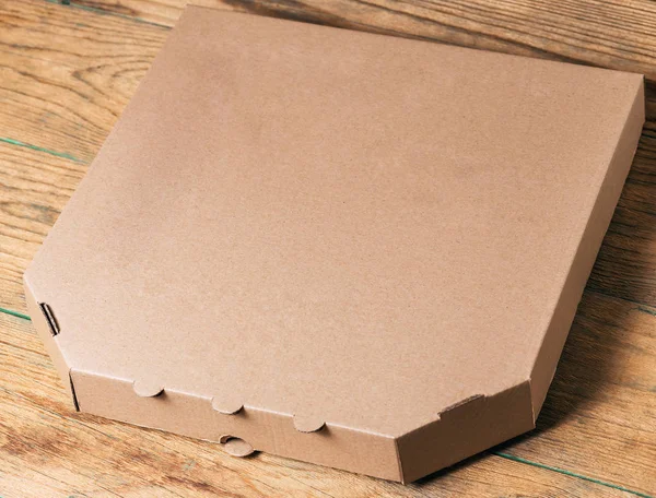 Empty cardboard pizza box on wooden table — Stock Photo, Image