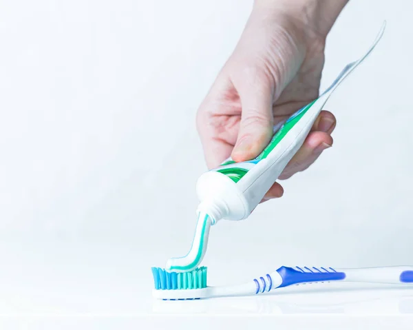 Pasta de dentes e uma escova em uma mão de homem isolada em branco — Fotografia de Stock