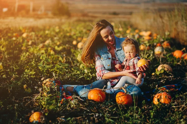 Mor och dotter på en åker med pumpor — Stockfoto