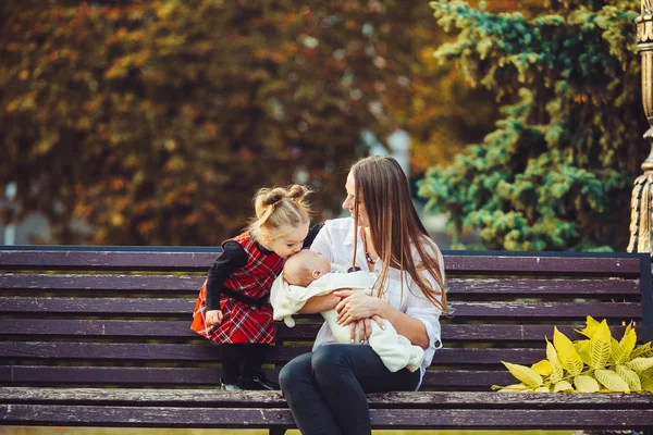 Madre y dos hijas descansan en un banco —  Fotos de Stock