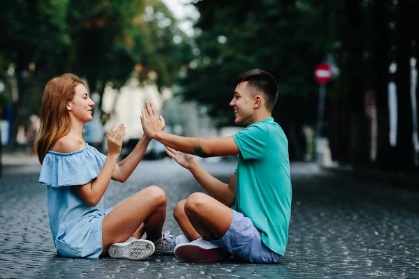 Pár sedí na chodníku náměstí — Stock fotografie