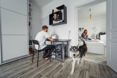 Dizüstü bilgisayar, anne ve bebek yatağı baba çalışıyor