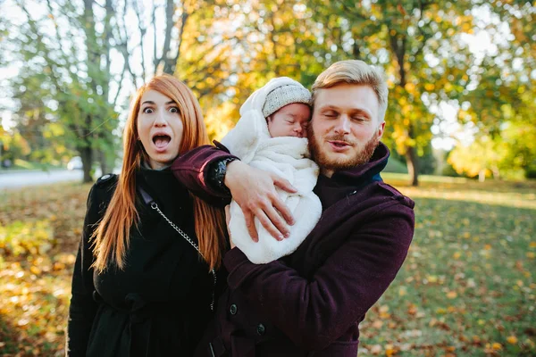 Jovem família e filho recém-nascido no parque de outono — Fotografia de Stock