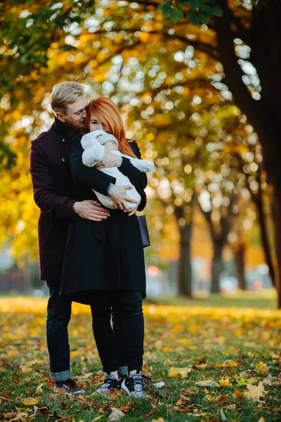 Familia joven e hijo recién nacido en el parque de otoño —  Fotos de Stock