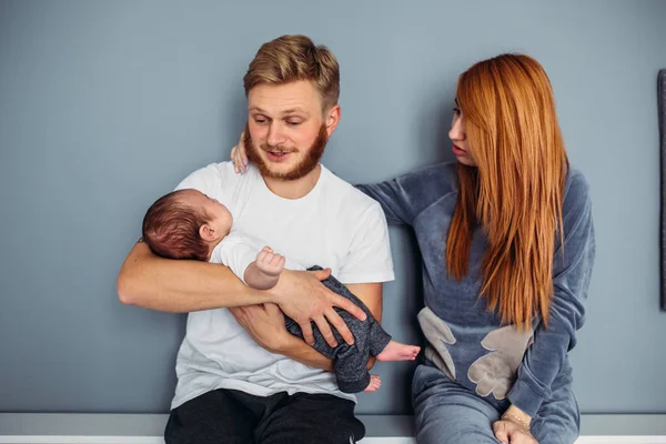 Familia joven con un bebé junto a la pared — Foto de Stock