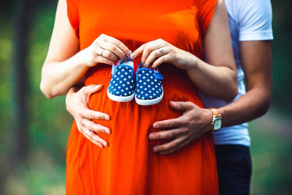 Mulher grávida e seu marido segurando sapatos de bebê — Fotografia de Stock