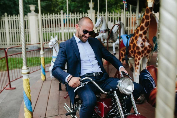 Hombre sentado en la motocicleta en el carrusel —  Fotos de Stock