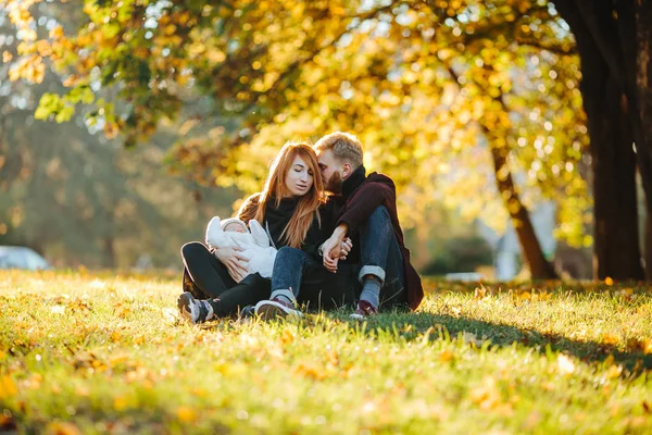 Familia joven e hijo recién nacido en el parque de otoño — Foto de Stock